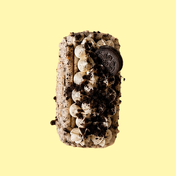 An Oreo-themed basque cheesecake with white frosting, dark chocolate cookie crumbs, and a whole Oreo cookie on top, presented on a solid pale yellow background.
