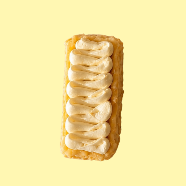 A single rectangular basque cheesecake topped with white cream topping on a pale yellow background. 